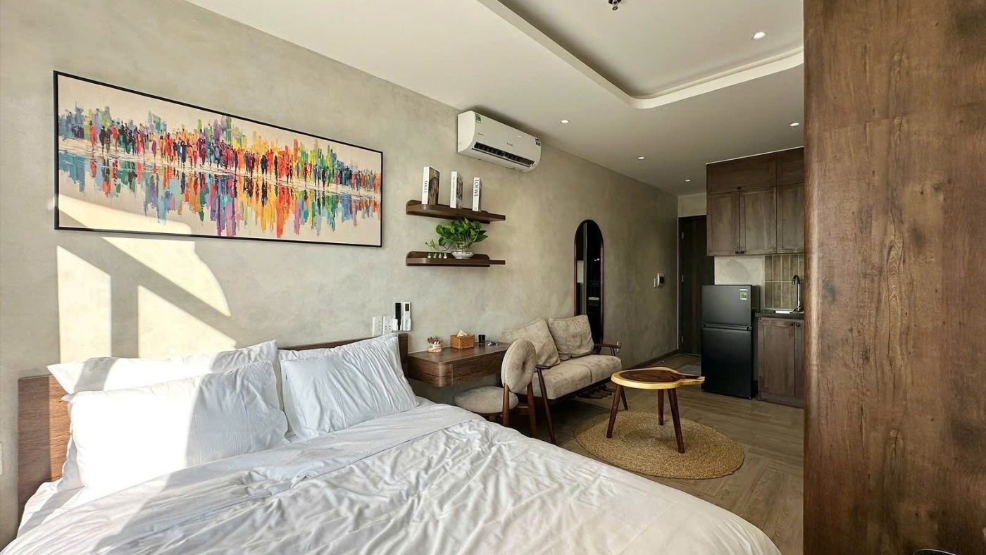 Phòng căn hộ dịch vụ có giường trắng, tranh treo tường và tủ gỗ