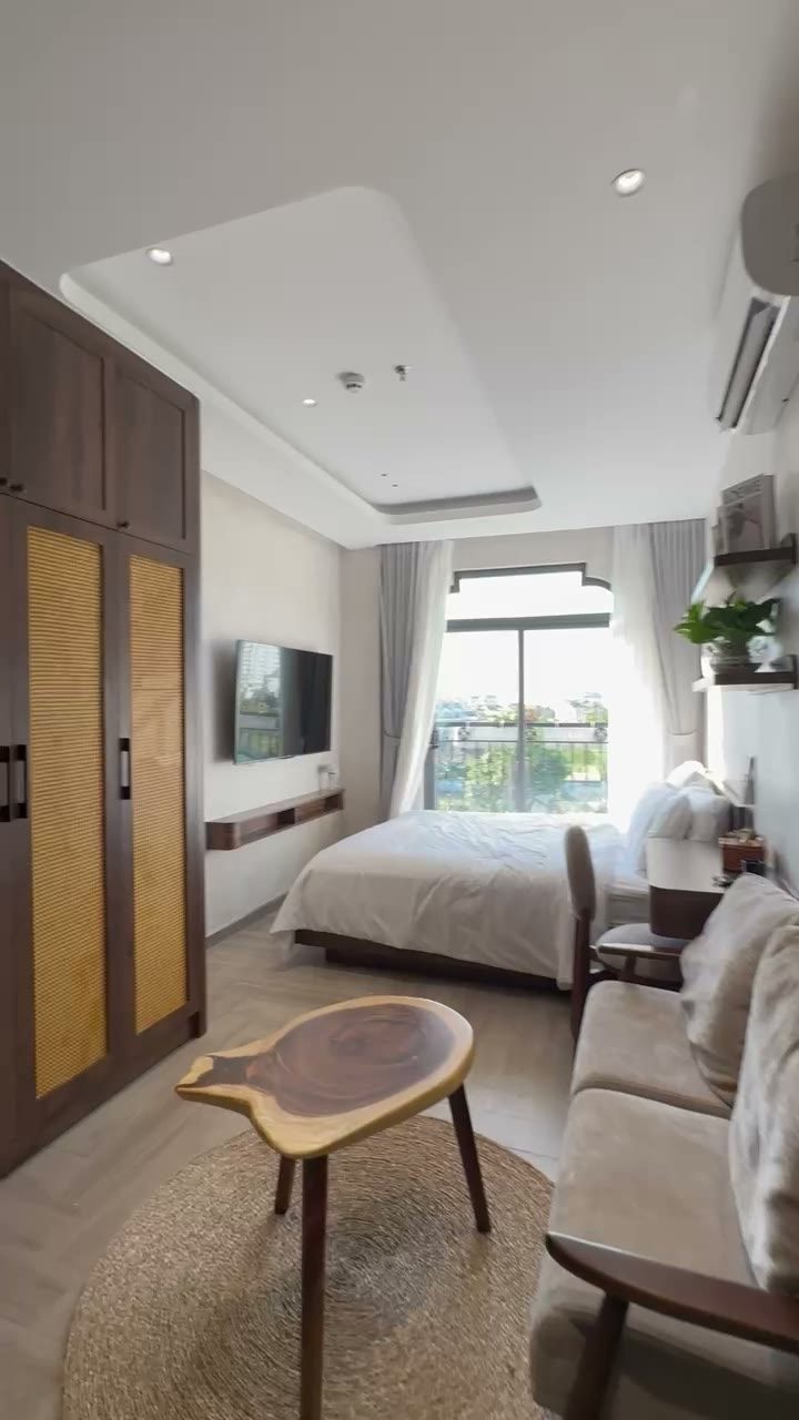 Phòng ngủ có giường, tủ gỗ, bàn trà và cửa sổ lớn