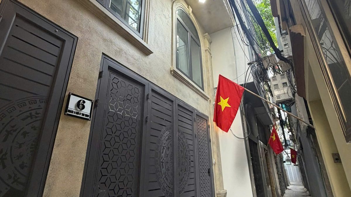 Ngõ nhỏ ở Hà Nội với cổng sắt tòa nhà cho thuê và cờ đỏ treo trên tường