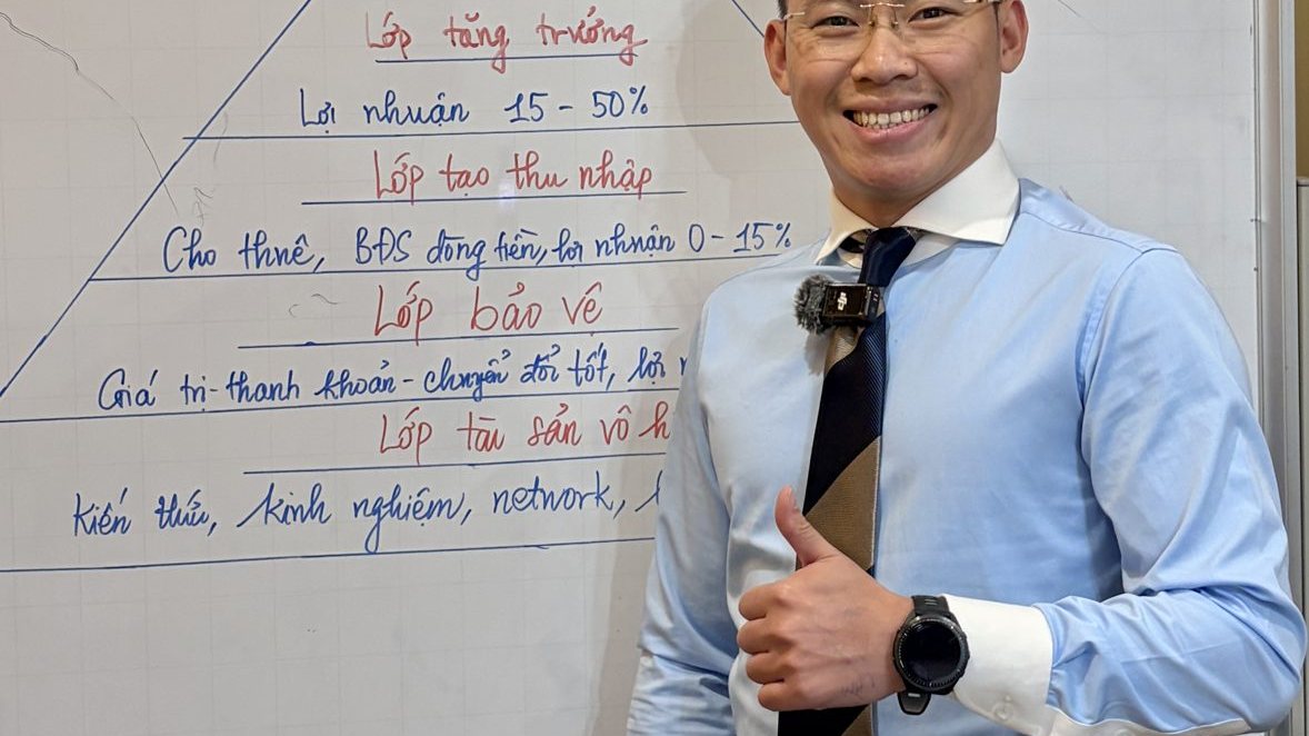 Lê Anh Tuấn đứng cạnh bảng trắng vẽ tháp lợi nhuận nhiều tầng