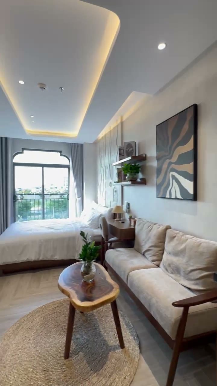 Phòng mặt trước có sofa, bàn trà gỗ và cửa sổ lớn