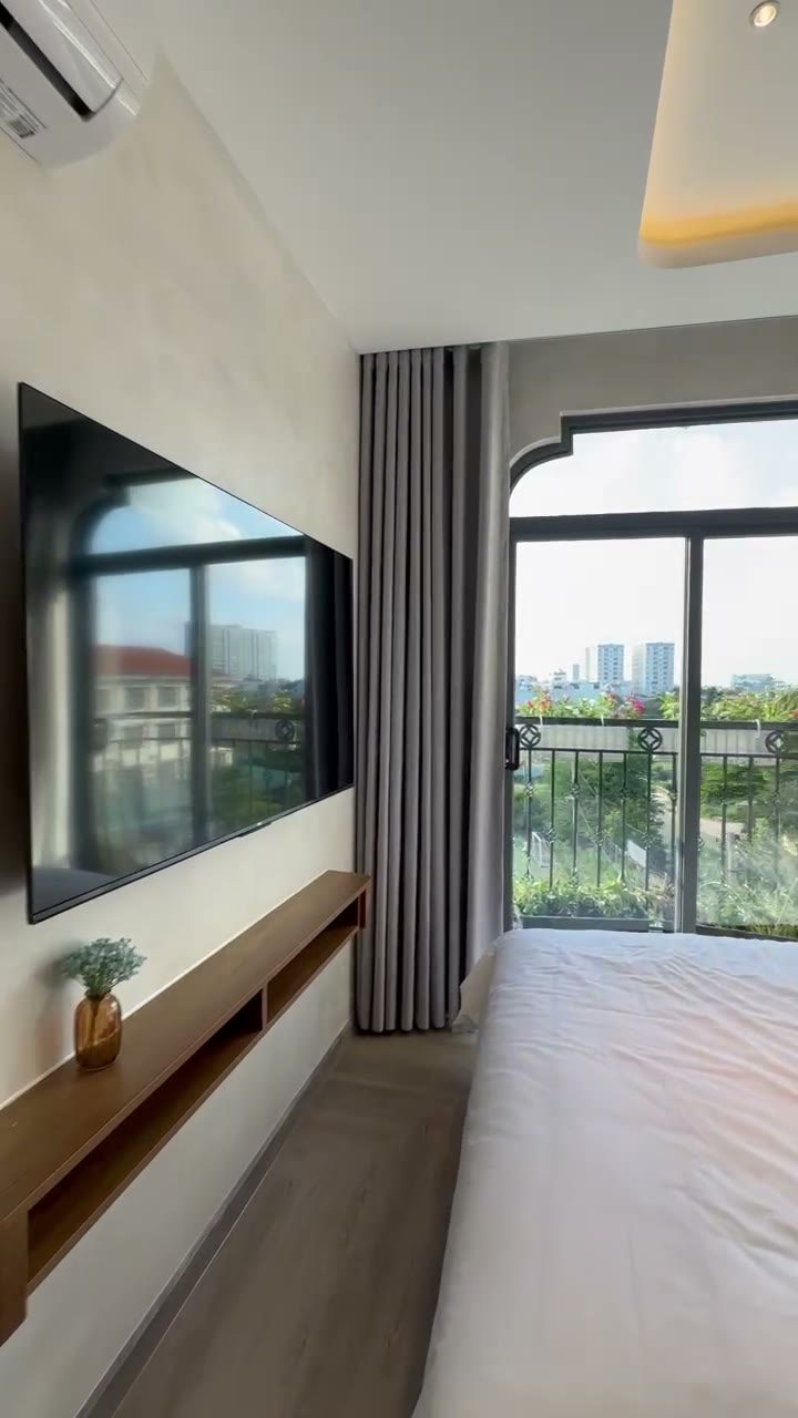 Phòng cho thuê có tivi treo tường, rèm và cửa kính lớn