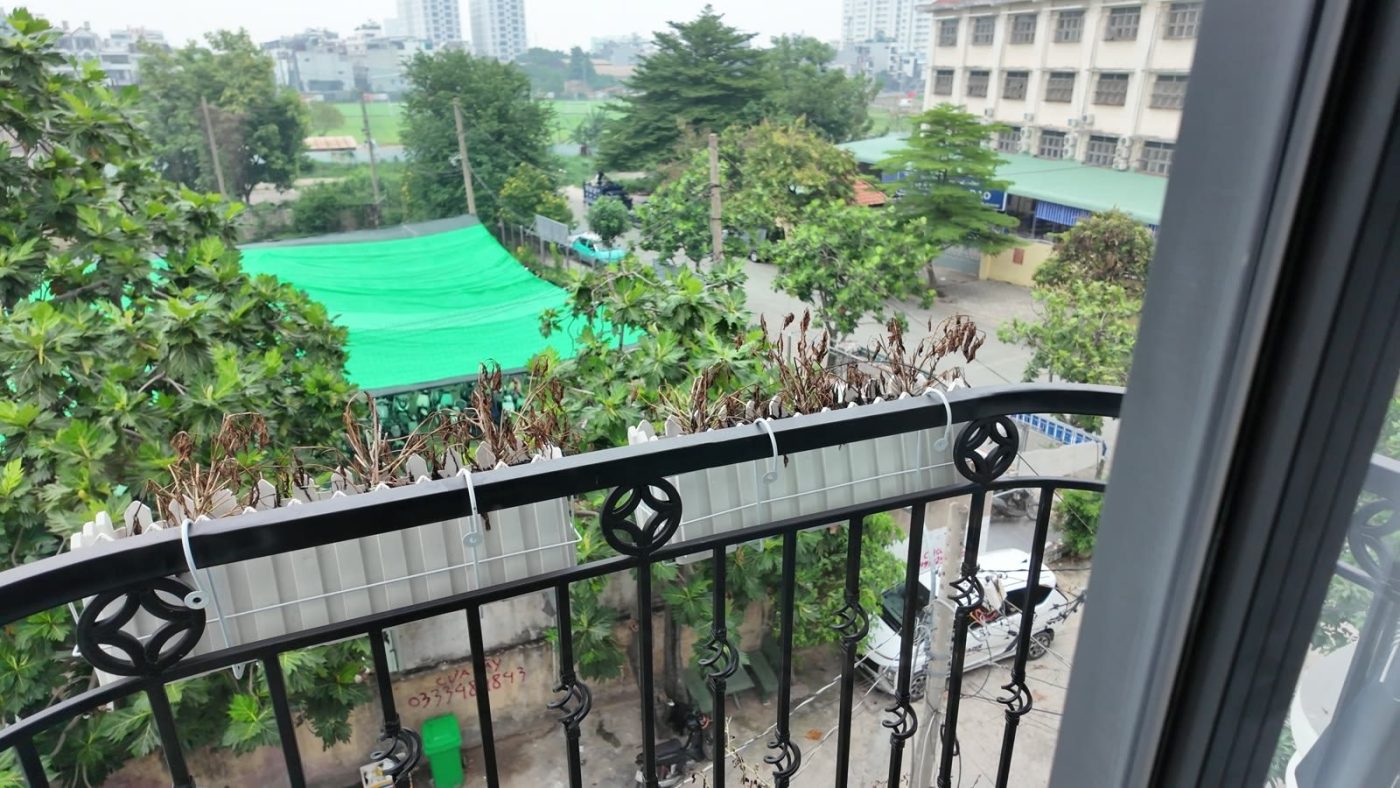 Ban công phòng mặt trước nhìn ra sân bóng xanh và hàng cây