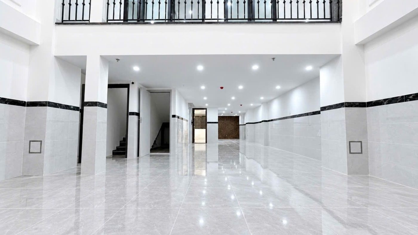 Tầng trệt rộng sàn gạch bóng của một tòa ở Phan Huy Ích, Gò Vấp, cột trắng và lan can sắt đen ở tầng lửng, ảnh bìa bài viết về bán căn hộ dịch vụ Gò Vấp