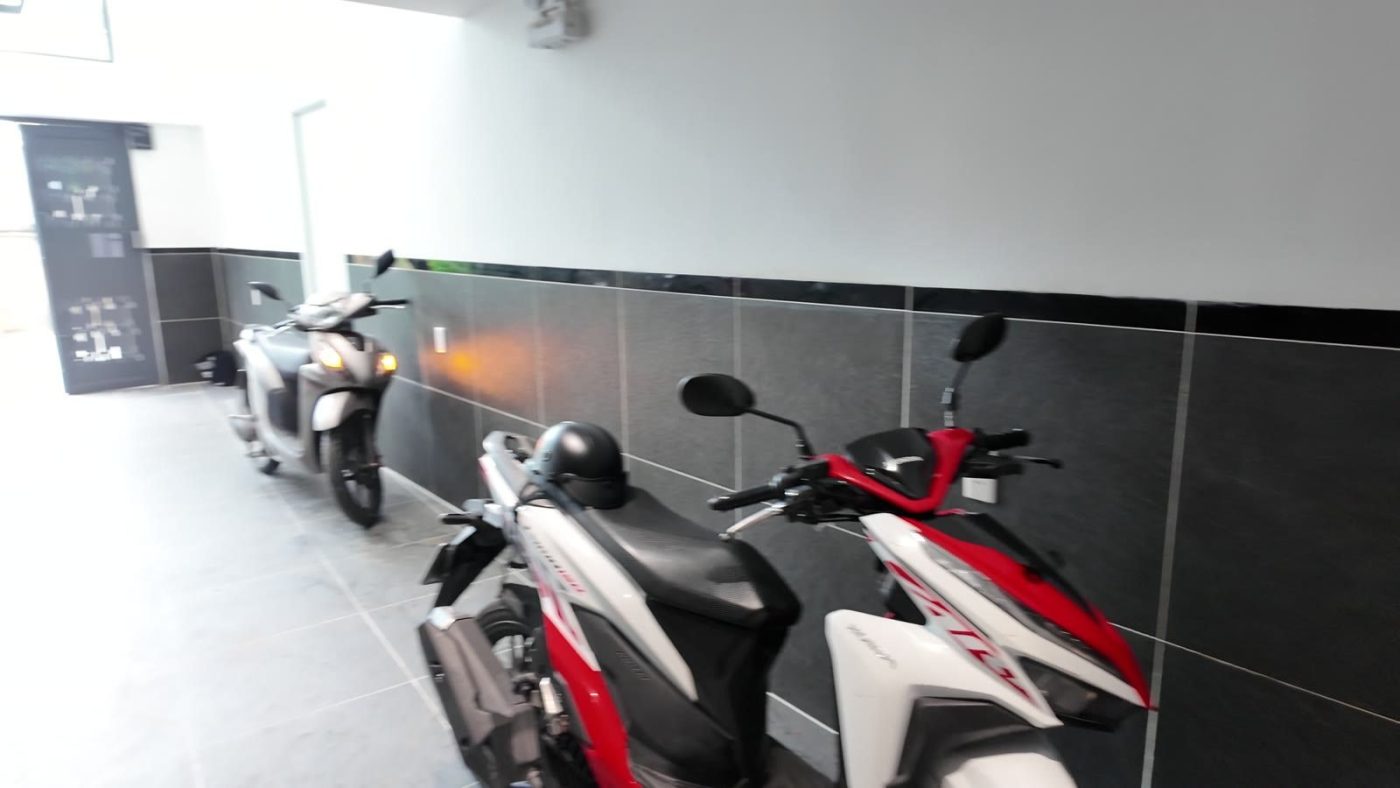 Xe máy đỗ sát tường ốp đá đen ở sảnh tầng trệt một tòa nhà cho thuê, ảnh bìa bài viết về bán nhà không ai mua