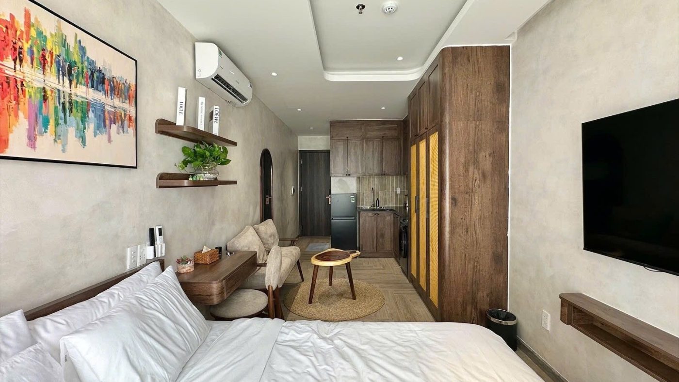 Phòng cho thuê nhìn từ giường thấy tranh nhiều màu, tivi treo tường, tủ gỗ và góc bếp phía cuối phòng, ảnh bìa bài viết về bảng chấm điểm nhà dòng tiền