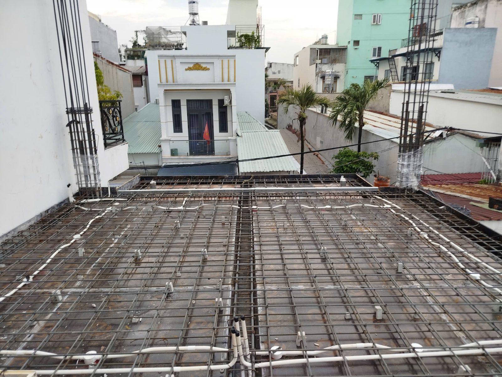Sàn mái đang đặt cốt thép và ống luồn dây điện, phía xa là các nhà dân