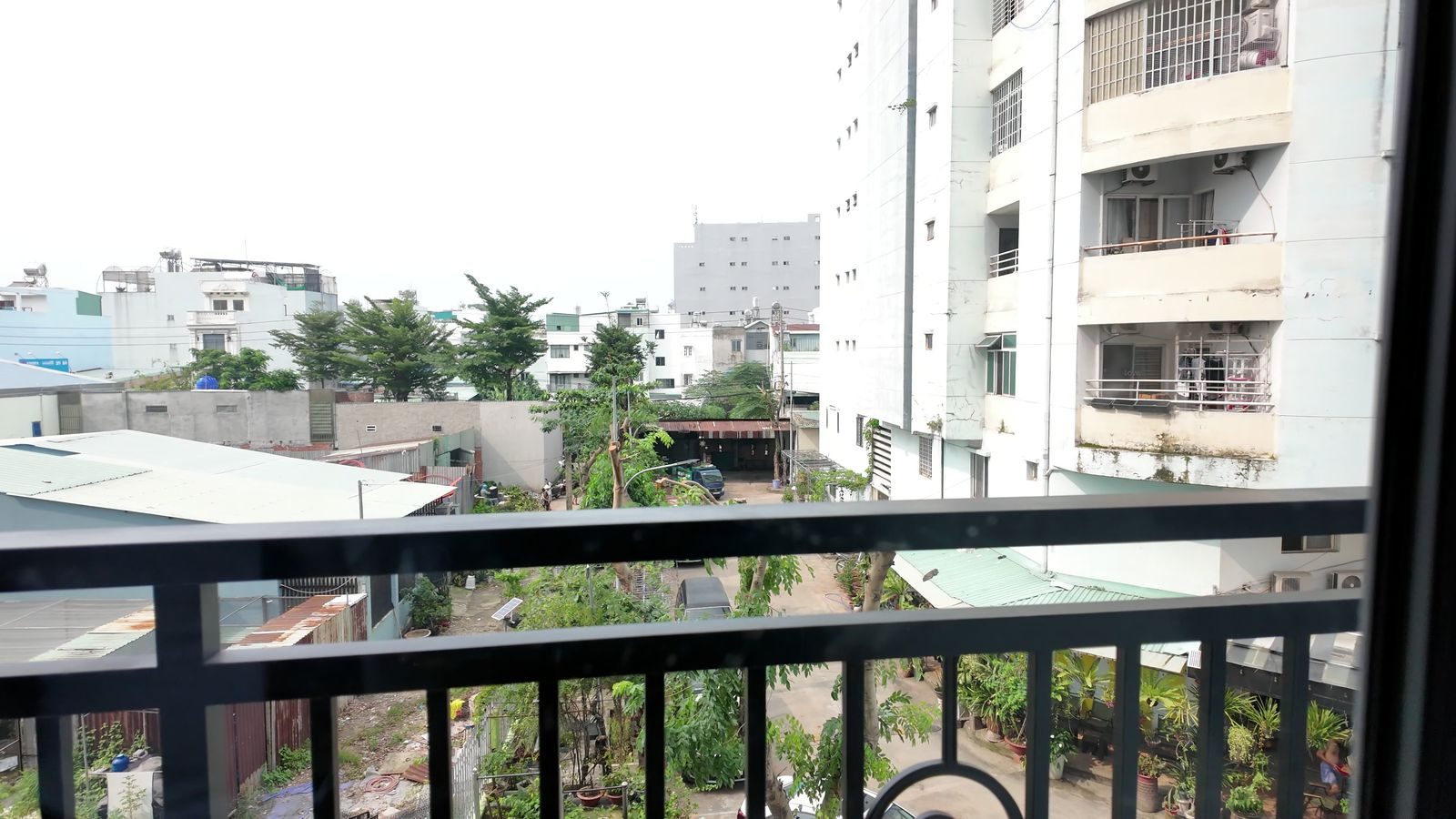 Nhìn từ ban công xuống khu nhà thấp tầng, bên cạnh là một tòa chung cư cao tầng