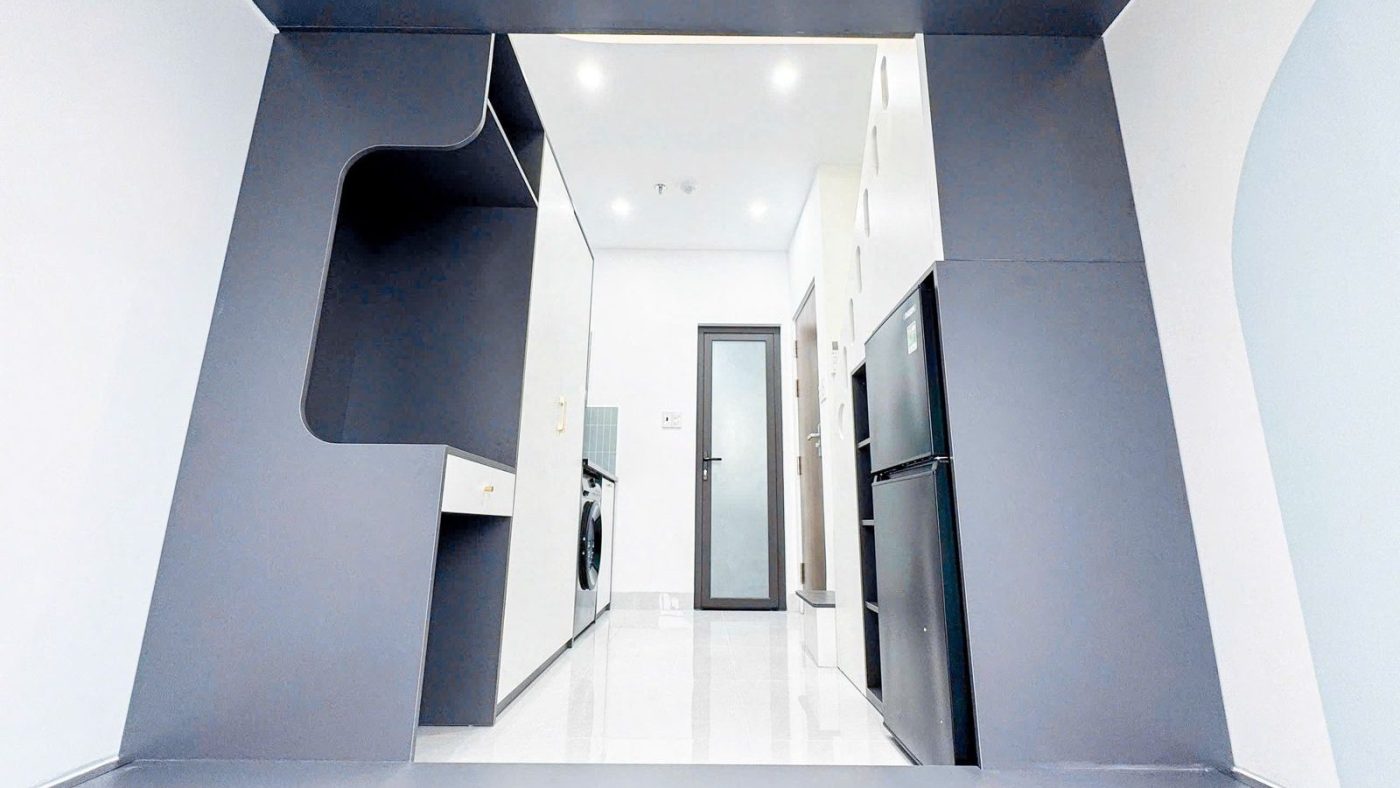 Phòng cho thuê nhìn từ dưới gác lửng, có tủ lạnh, tủ áo và cửa ra vào ở cuối phòng