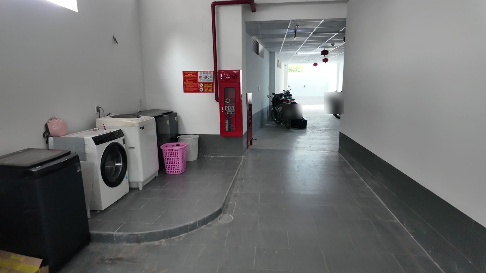 Tầng trệt tòa nhà cho thuê có máy giặt dùng chung, tủ chữa cháy và lối để xe