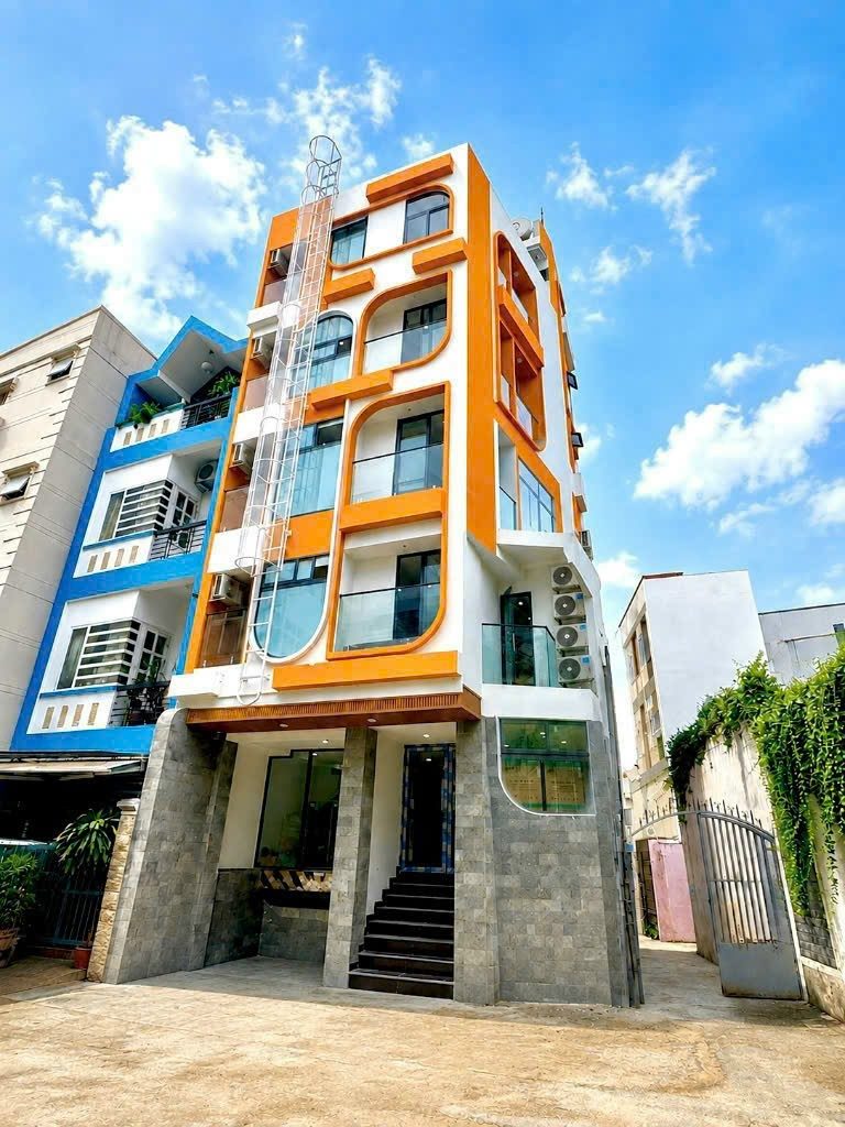 Tòa nhà cho thuê năm tầng sơn cam, trắng với ban công cong và thang sắt thoát hiểm bên hông