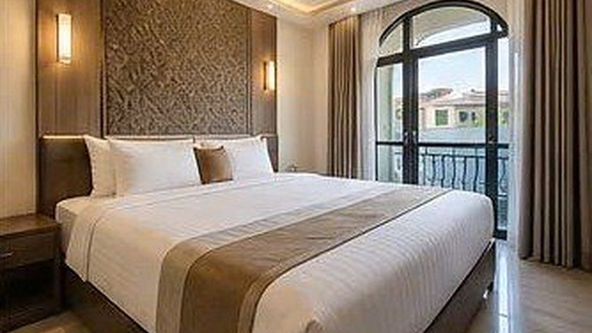 Phòng ngủ kiểu khách sạn có giường lớn, đèn tường và cửa vòm ra ban công, ảnh bìa bài viết về cho thuê theo ngày cần giấy phép gì