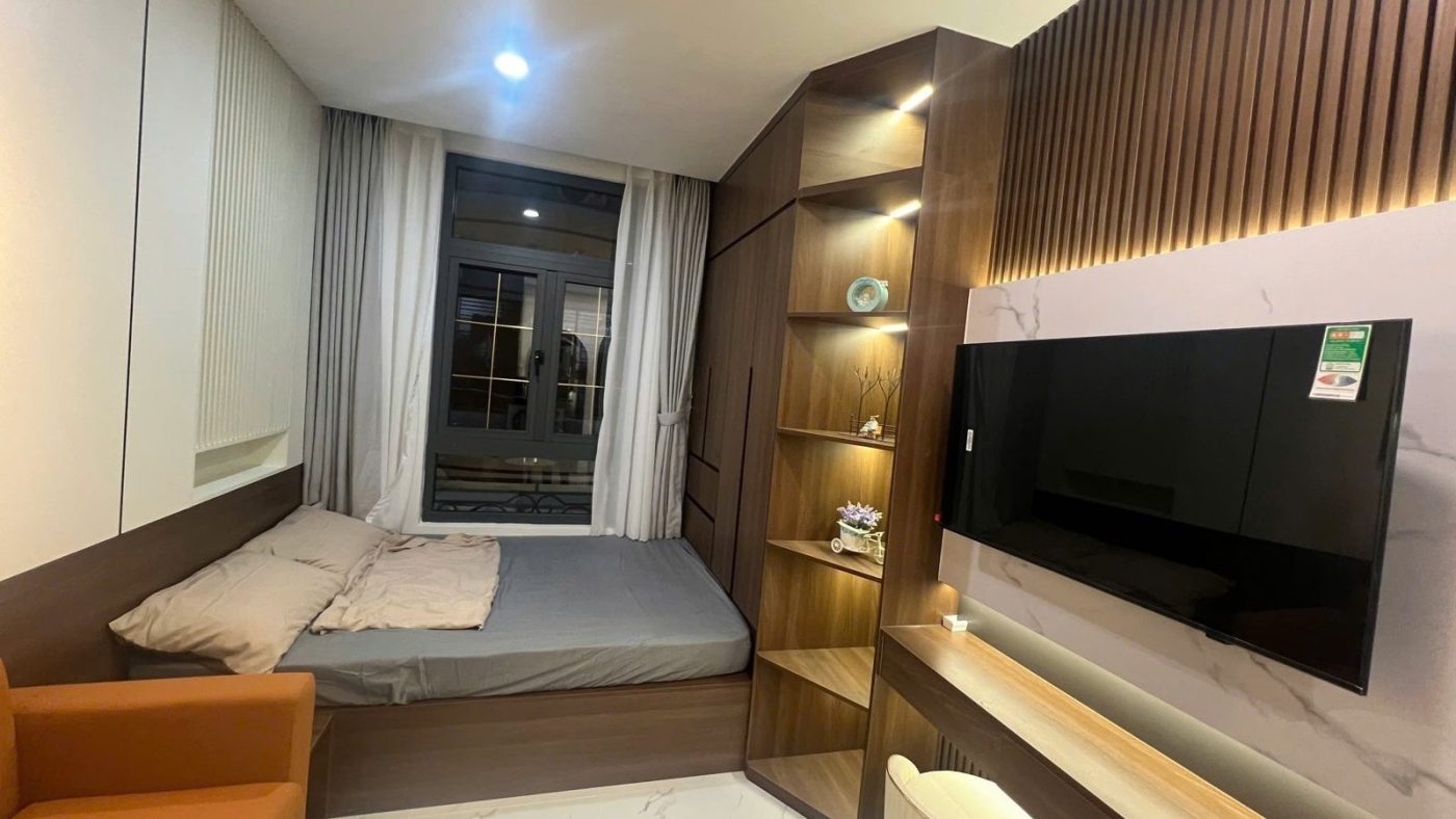 Phòng ngủ ốp gỗ nan có giường, tivi treo tường và kệ đèn hắt, ảnh bìa bài viết về chuyển từ cổ phiếu sang bất động sản