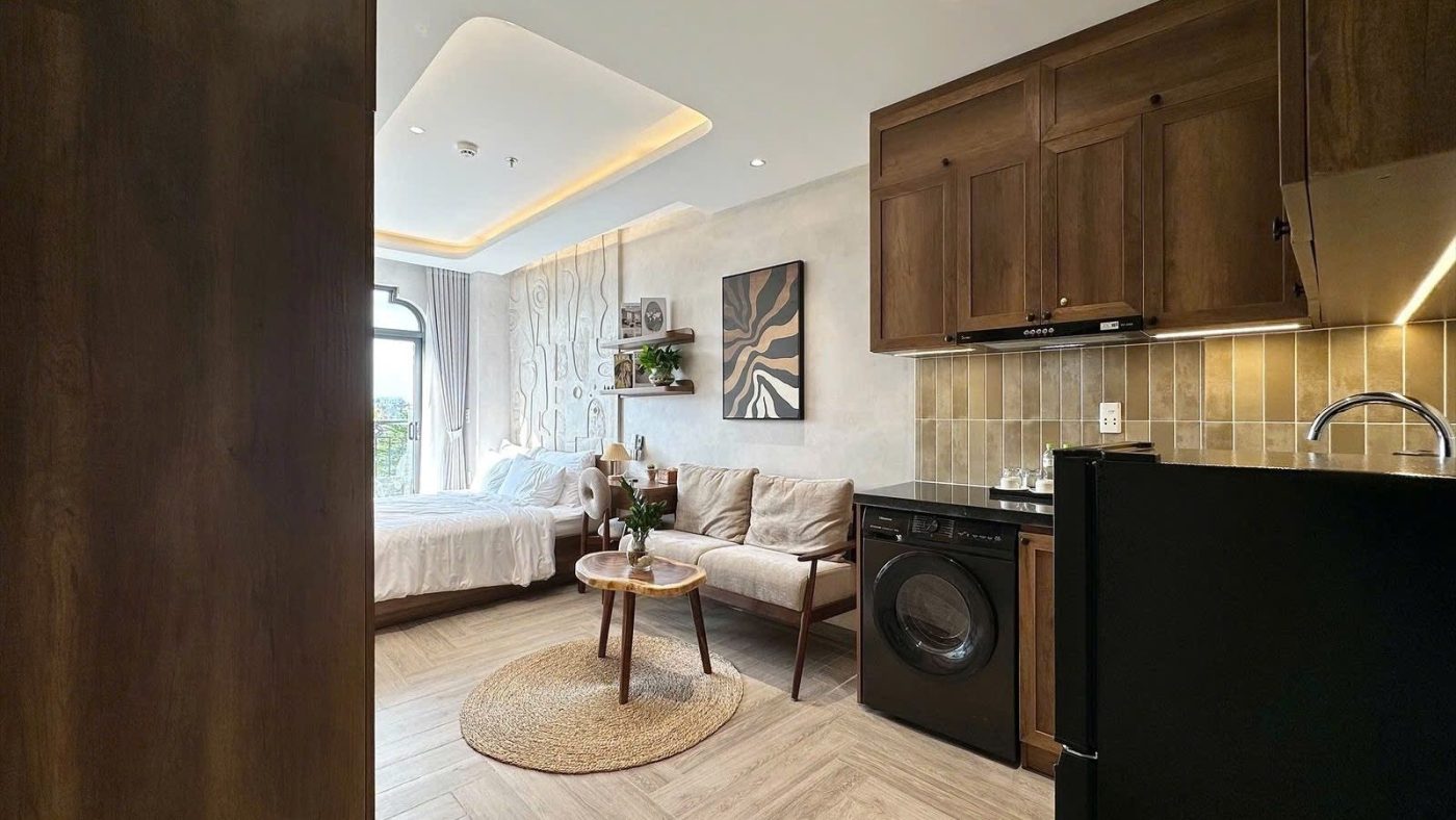 Phòng cho thuê nhìn từ cửa vào, có bếp gỗ, máy giặt, bộ sofa và giường cạnh cửa sổ, ảnh bìa bài viết về có 6 tỷ mua nhà cho thuê