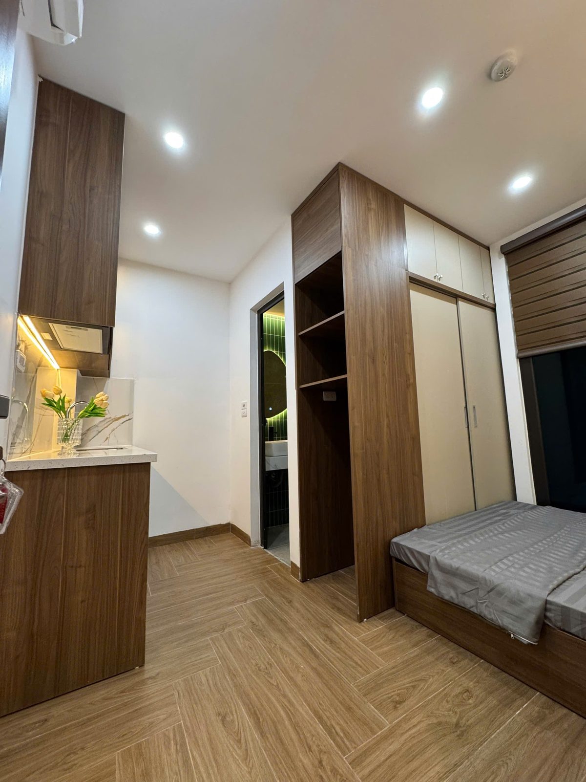 Lối vào phòng cho thuê có tủ bếp, tủ áo gỗ và giường ở cuối phòng