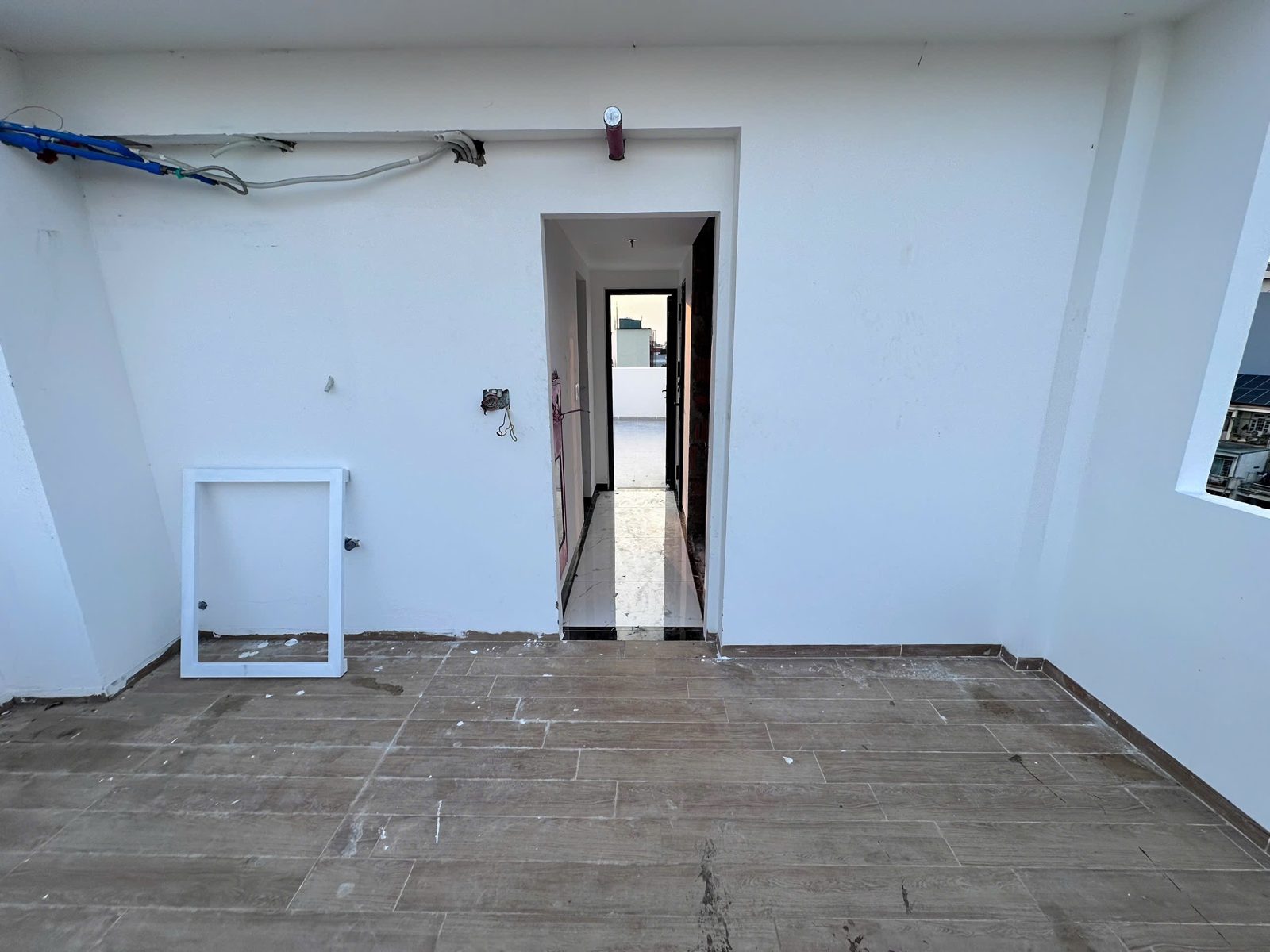 Một tầng nhà đang hoàn thiện, sàn lát gạch giả gỗ, tường trắng, chưa có nội thất