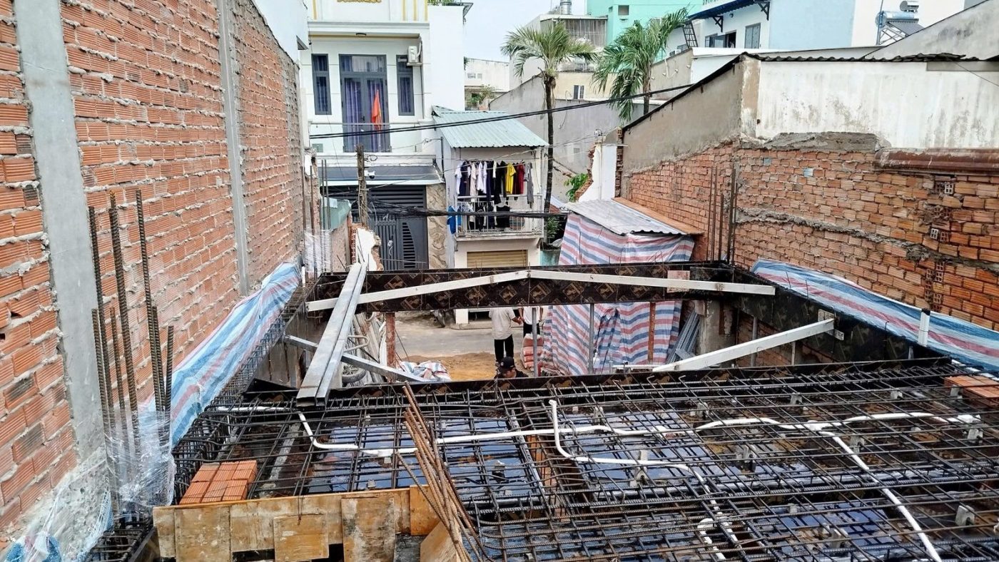 Thép sàn đang đan trên một lô đất hẹp giữa hai bức tường gạch, ảnh bìa bài viết về diện tích thực tế nhỏ hơn sổ