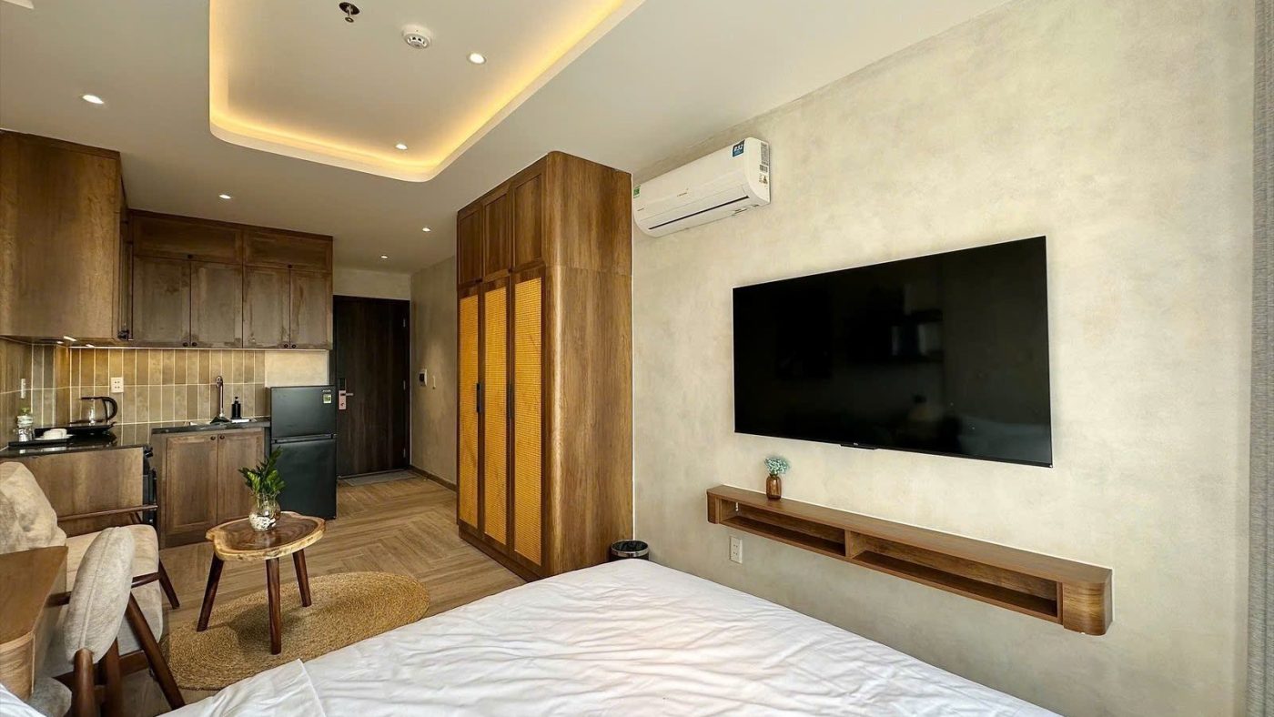 Phòng cho thuê nhìn từ giường thấy tivi treo tường, tủ gỗ, góc bếp và bàn trà, ảnh bìa bài viết về giả định khi tính dòng tiền cho thuê