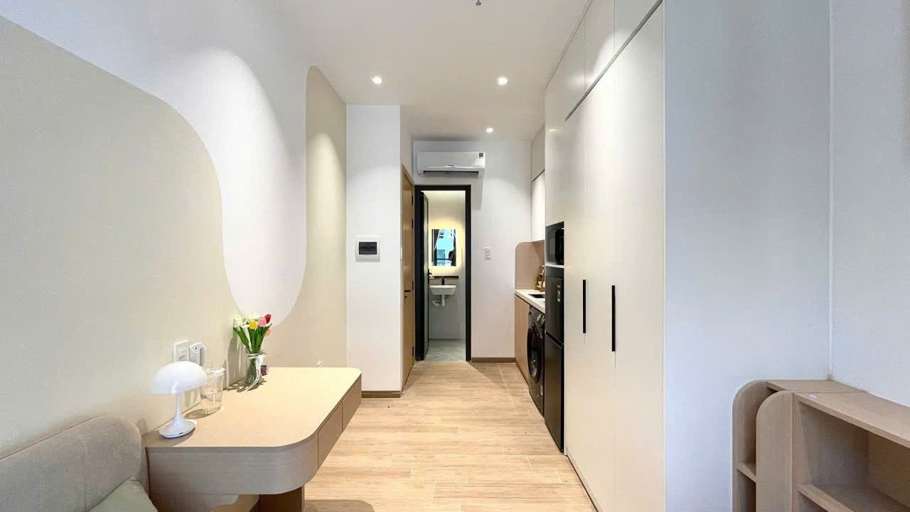Phòng cho thuê có bục giường, tủ trắng bo cong và lối vào phòng tắm phía trong, ảnh bìa bài viết về góp vốn mua chung nhà
