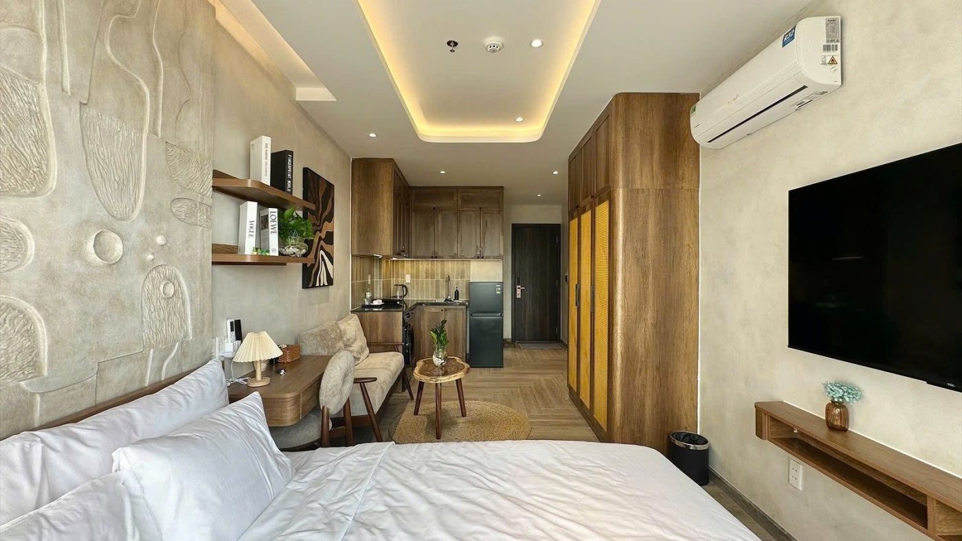 Giường trải ga trắng trong phòng cho thuê có tường phù điêu, tivi treo tường và kệ gỗ dài, ảnh bìa bài viết về hết ưu đãi lãi suất
