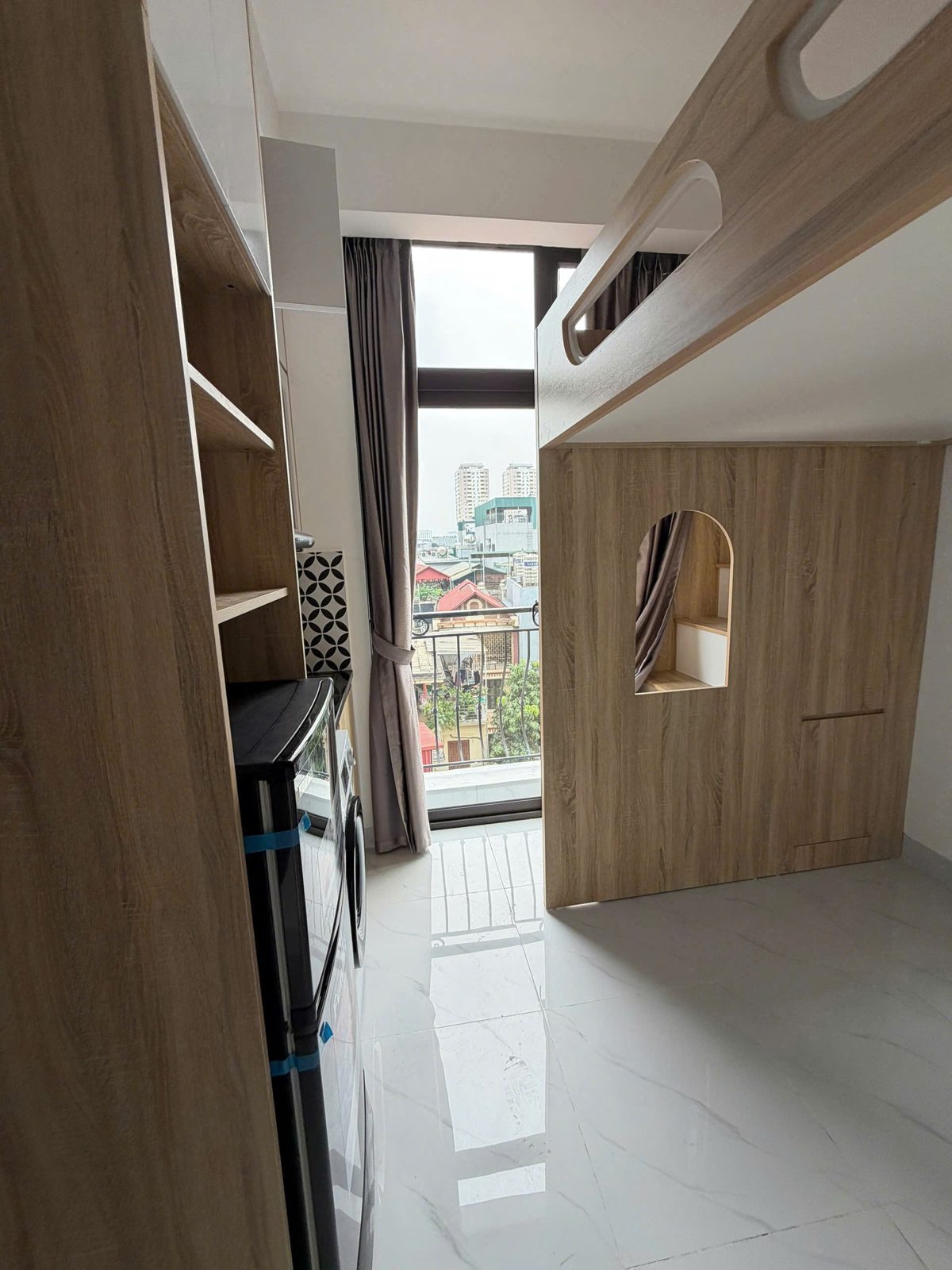 Phòng cho thuê có giường gác bằng gỗ và cửa kính lớn nhìn ra phố