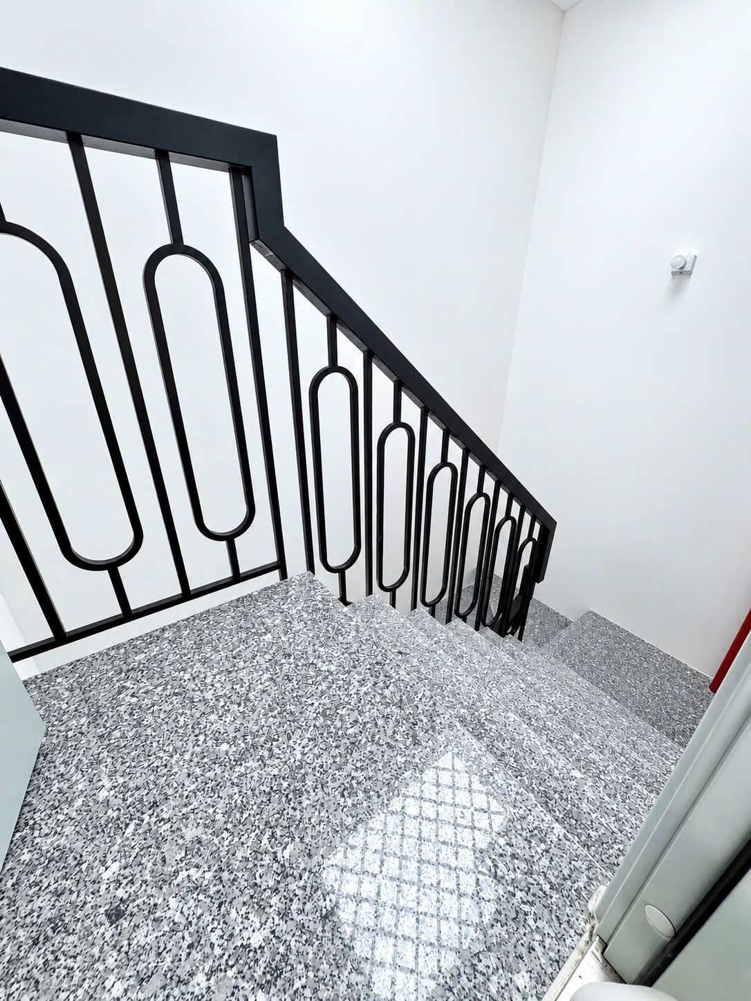 Cầu thang bộ lát đá granite có lan can sắt đen trong một tòa nhà cho thuê