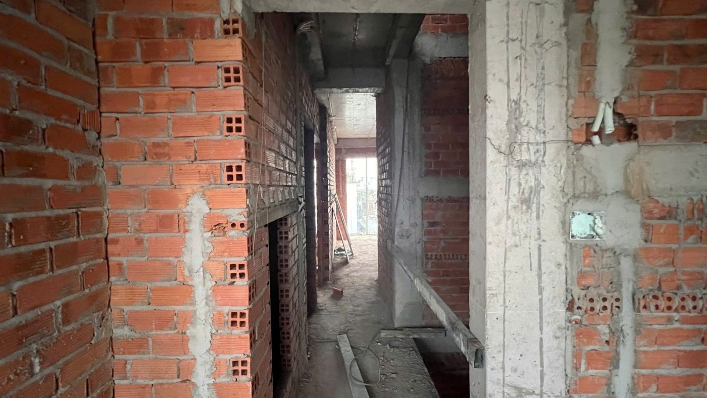 Hành lang hẹp giữa hai bức tường gạch của một tòa nhà đang xây, ảnh bìa bài viết về lối thoát nạn thứ hai