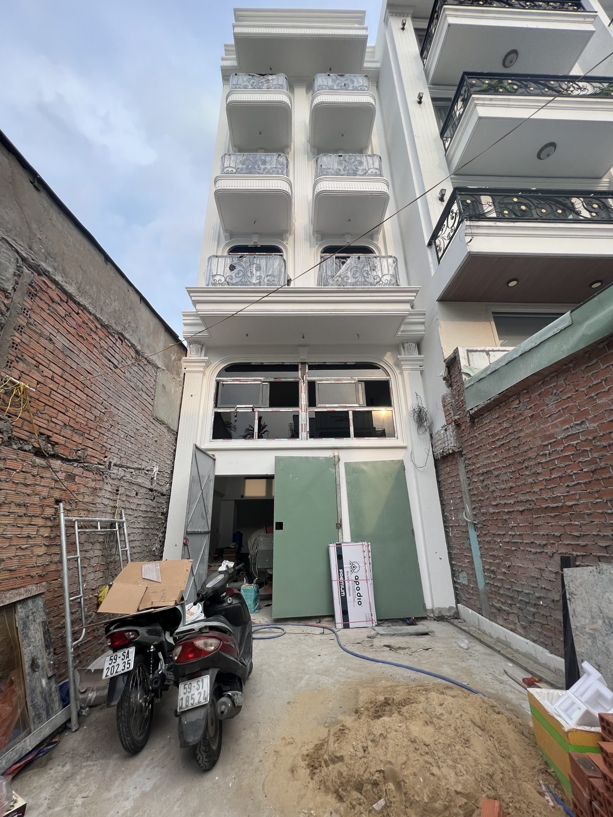 Mặt tiền tòa nhà năm tầng đang hoàn thiện, phía trước còn vật liệu xây dựng