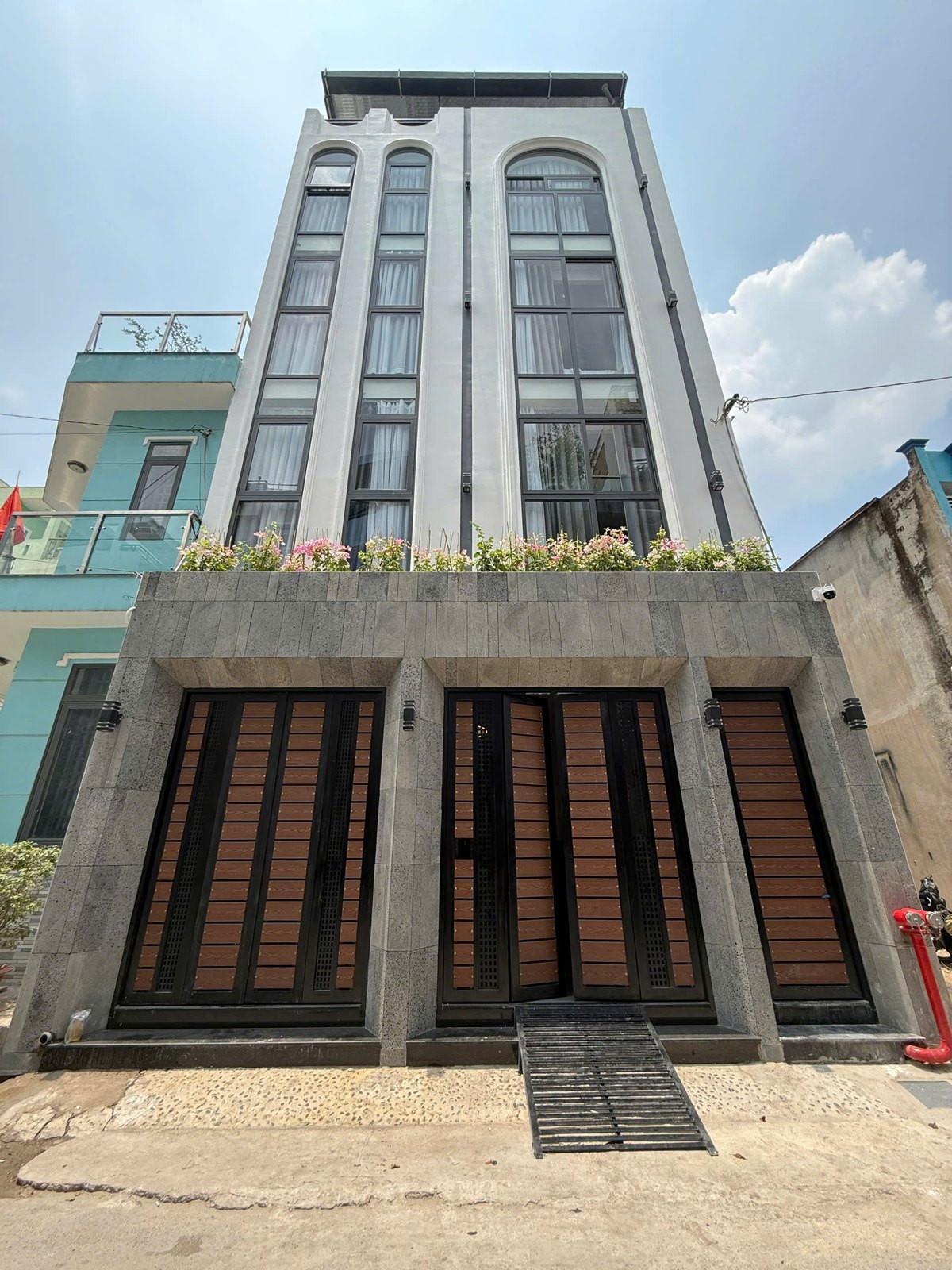 Mặt tiền tòa nhà cho thuê năm tầng có cửa sắt nâu và hoa trên ban công