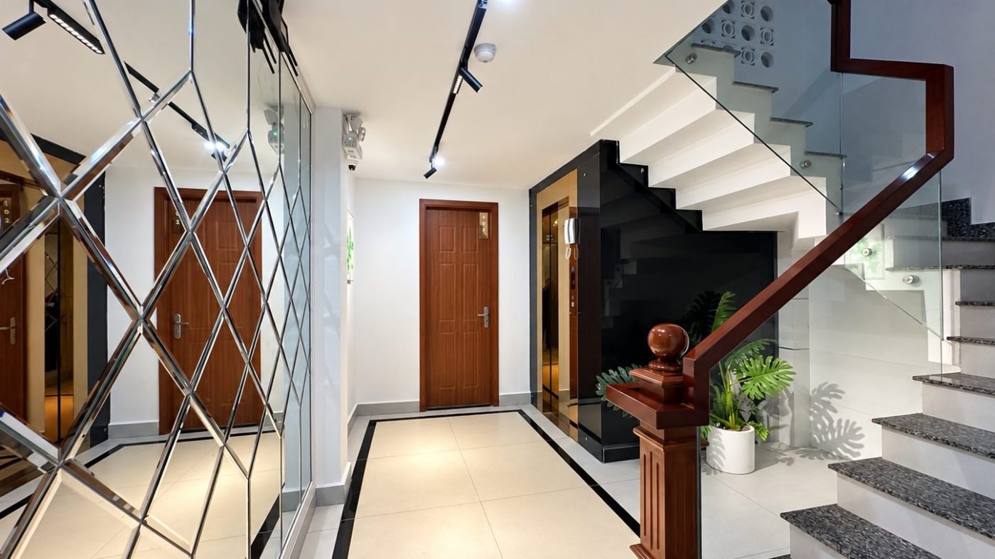 Chiếu nghỉ cầu thang có vách gương, cửa phòng gỗ và lan can kính, ảnh bìa bài viết về lý do bán nhà của chủ