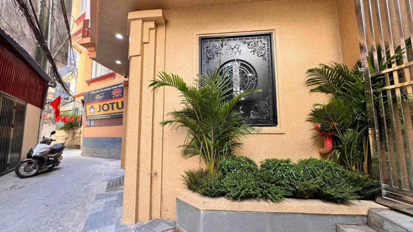 Lối vào một tòa nhà cho thuê trong ngõ ở Hà Nội, có bồn cây cọ và cửa sắt hoa văn