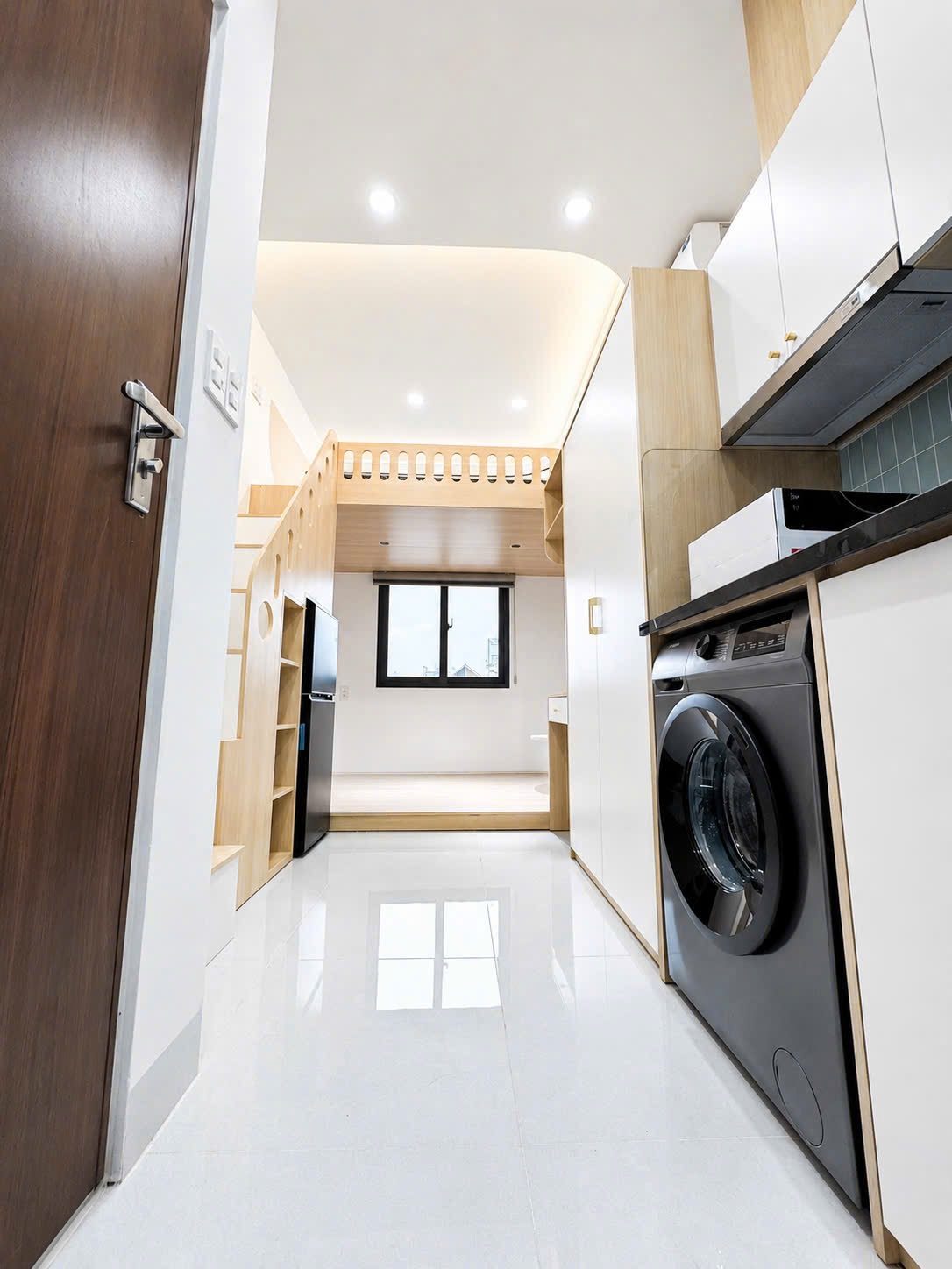 Cửa phòng gỗ mở vào một phòng cho thuê có bếp, máy giặt và gác lửng