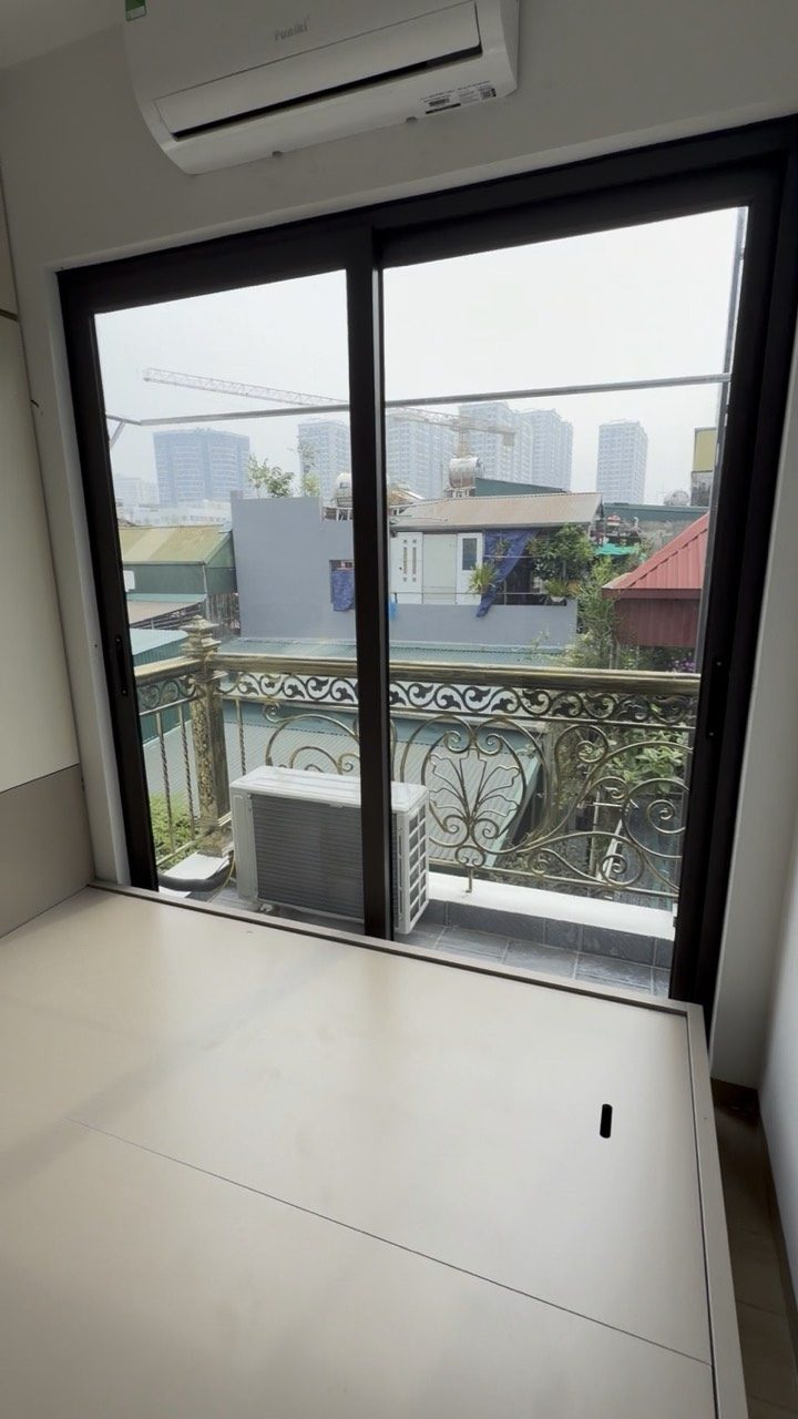 Phòng cho thuê còn trống có cửa kính ra ban công, nhìn ra khu nhà xung quanh