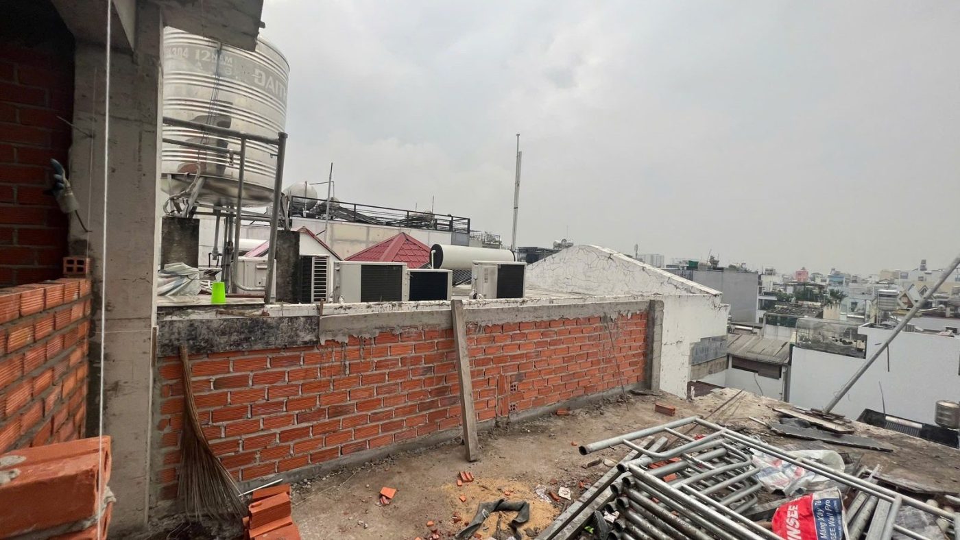 Sân thượng một tòa nhà đang xây, tường gạch mới và giàn giáo, nhìn ra khu dân cư, ảnh bìa bài viết về nguồn cung phòng cho thuê