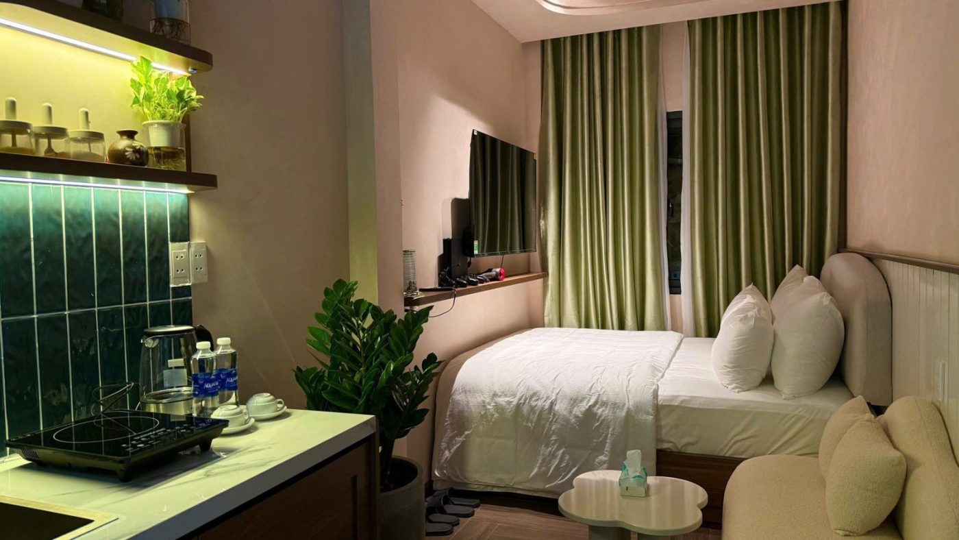 Căn hộ dịch vụ có bếp ốp gạch xanh, giường và rèm cửa màu xanh, ảnh bìa bài viết về nhà cho thuê gần ga metro