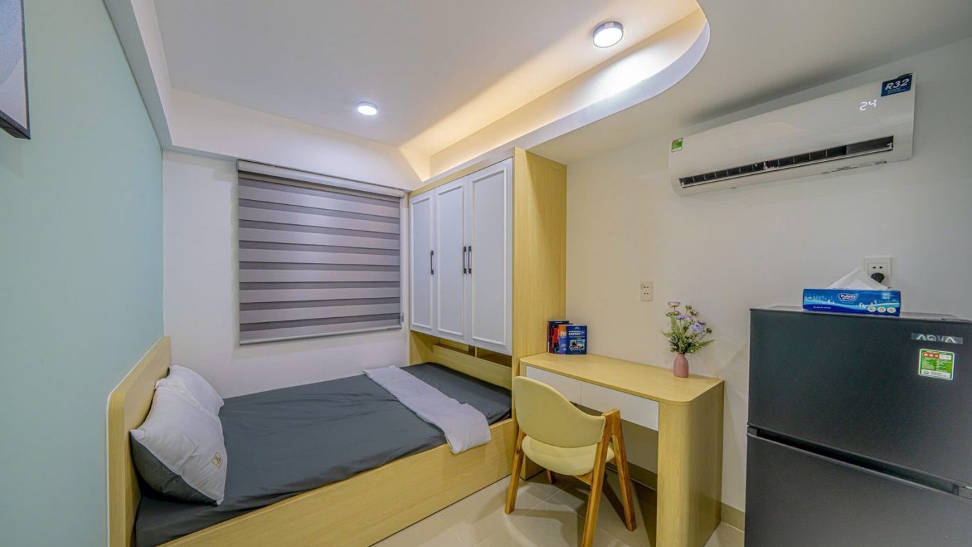 Phòng cho thuê nhỏ tường xanh nhạt có giường bục, bàn học và tủ lạnh, ảnh bìa bài viết về nhà cho thuê Thủ Đức