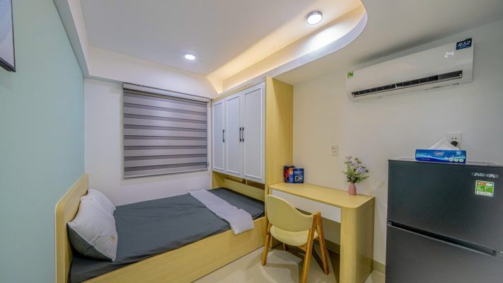 Phòng cho thuê nhỏ tường xanh nhạt có giường bục, bàn học và tủ lạnh, ảnh bìa bài viết về nhà cho thuê Thủ Đức