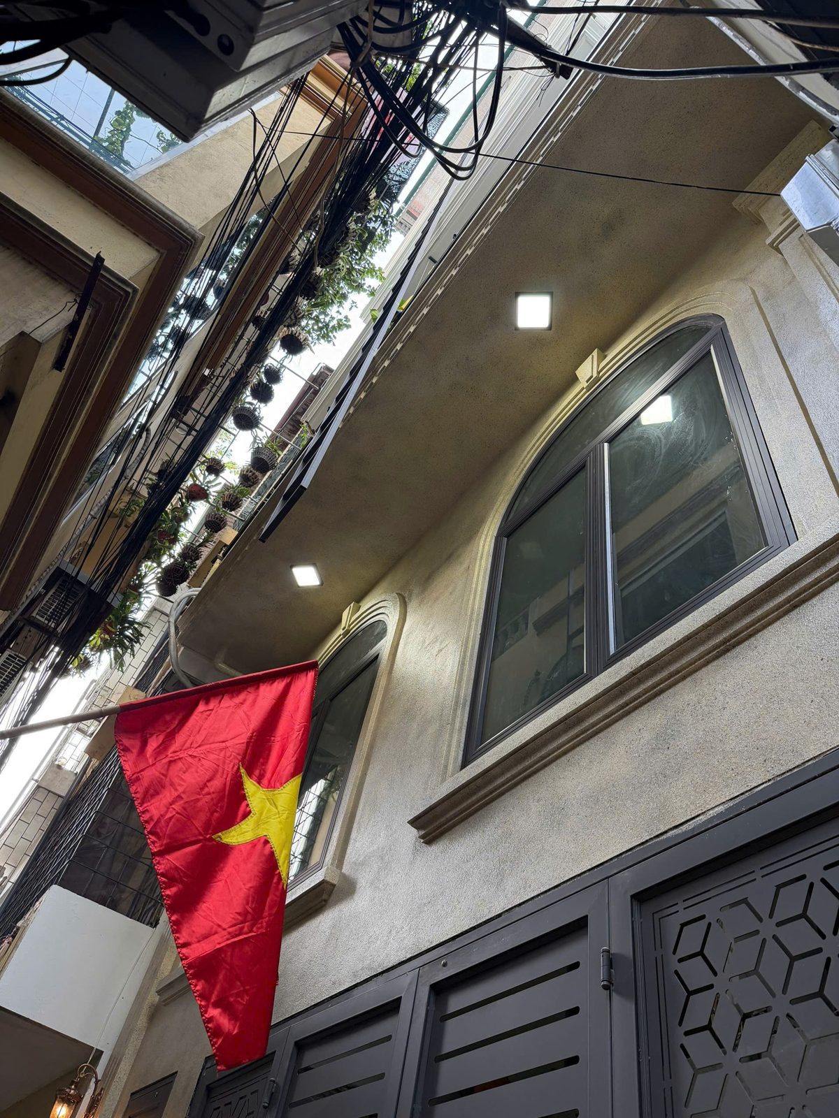 Mặt trước một căn nhà trong ngõ nhìn từ dưới lên, cửa sổ vòm và lá cờ treo trước nhà