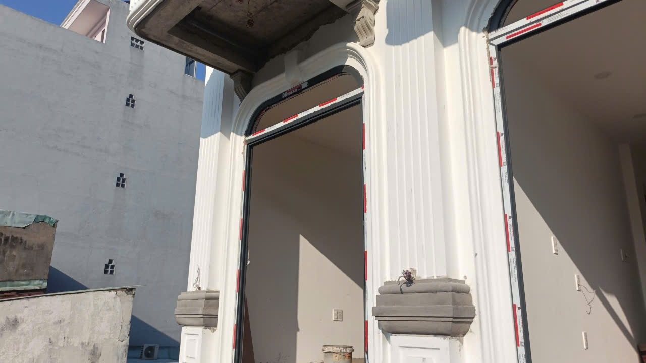 Mặt tiền một tòa nhà đang hoàn thiện, ô cửa vòm còn dán băng keo, ảnh bìa bài viết về nhà chưa hoàn công