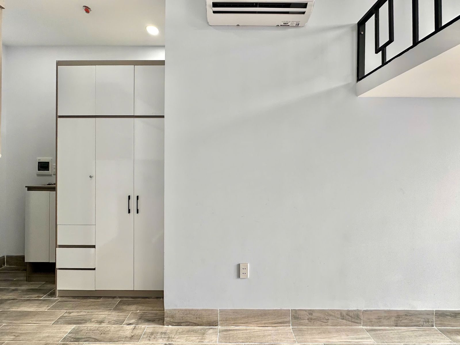 Tủ quần áo trắng cao sát trần và điều hòa trong phòng cho thuê có gác lửng