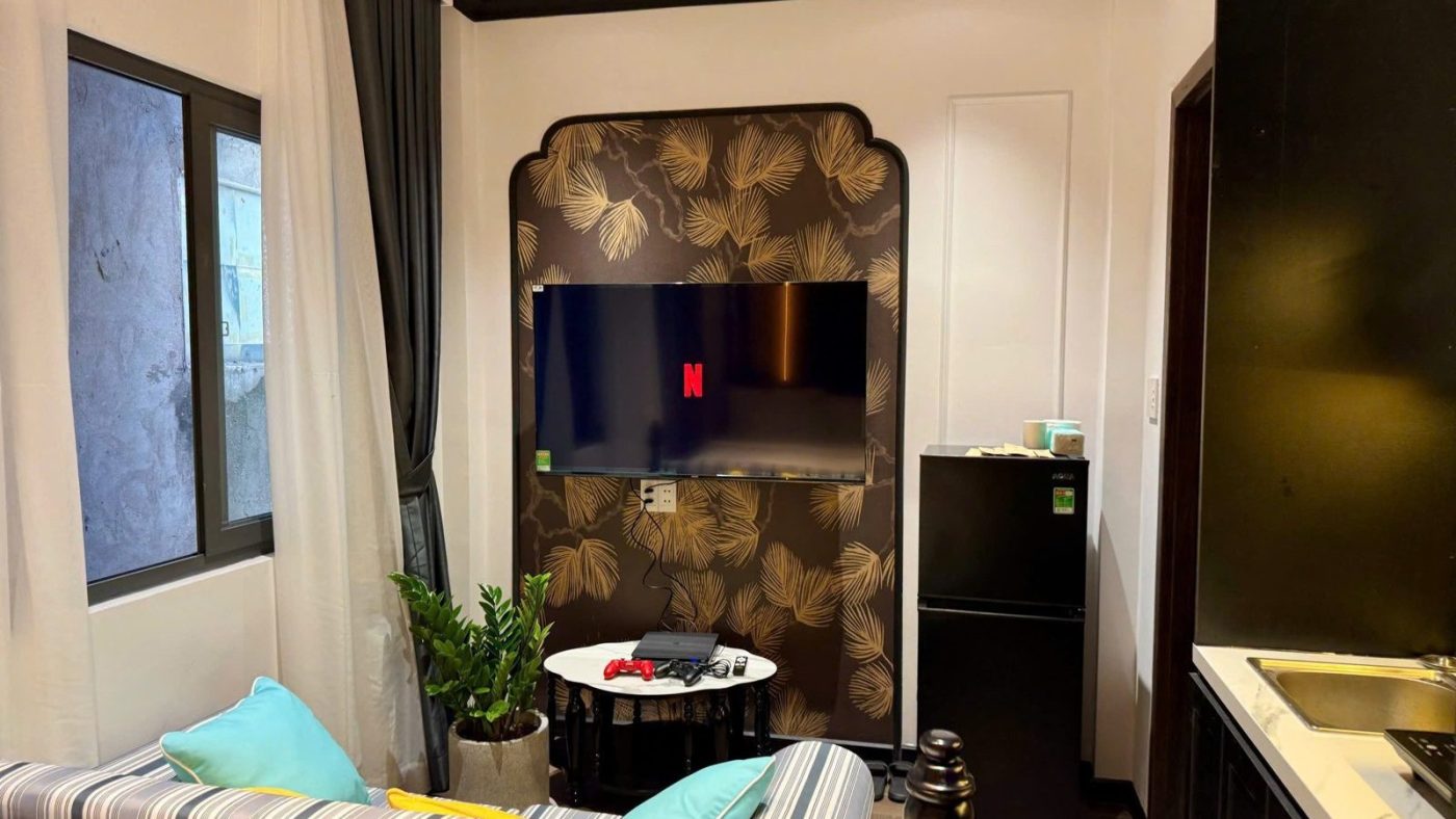 Phòng cho thuê trang trí kiểu Đông Dương, có tivi, ghế dài và tủ lạnh, ảnh bìa bài viết về phòng cho thuê giá rẻ hay phòng đẹp