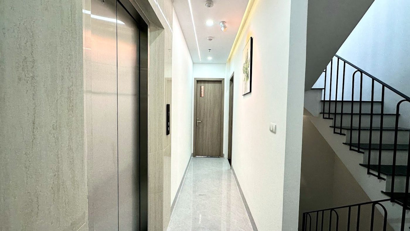 Hành lang một tòa nhà cho thuê có cửa thang máy, cầu thang bộ và camera trên trần, ảnh bìa bài viết về quản lý nhà cho thuê từ xa