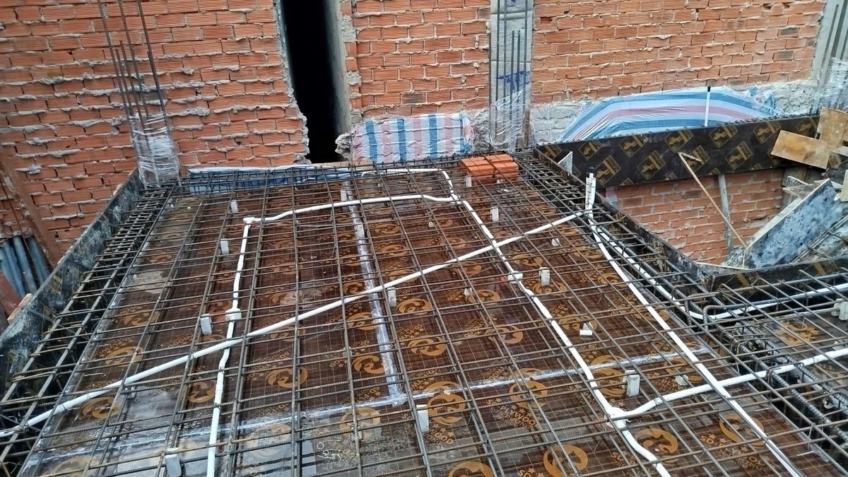 Sàn một tòa nhà đang xây, thép đã đan sẵn, ống điện đi trên sàn, xung quanh là tường gạch, ảnh bìa bài viết về tách giá đất và tiền xây