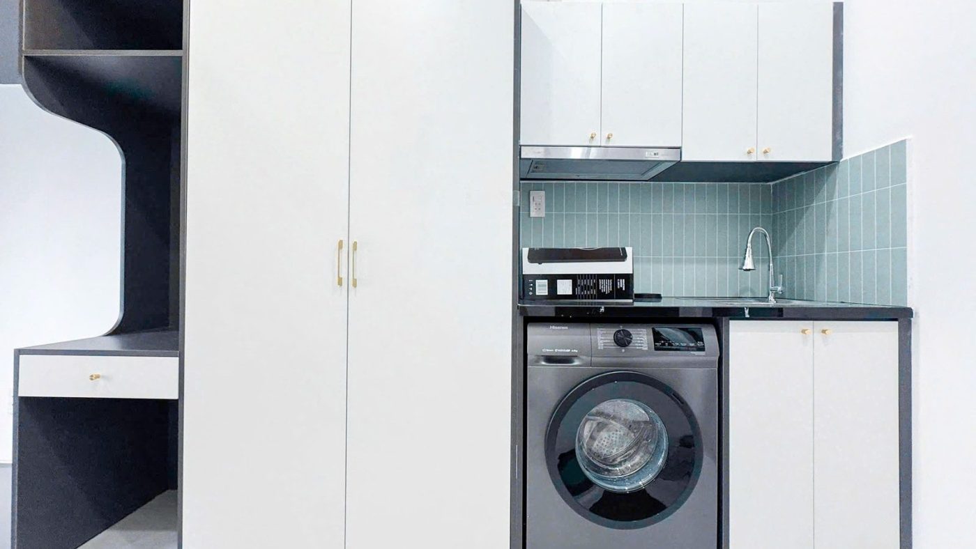 Phòng cho thuê có tủ áo trắng, bếp ốp gạch xanh, máy giặt và bàn làm việc dưới gác