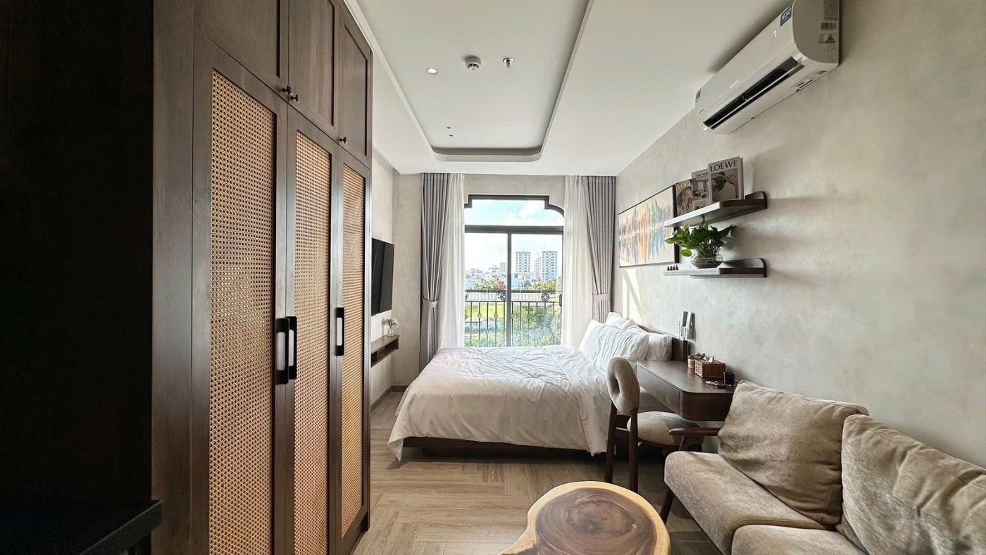 Phòng cho thuê có tủ áo gỗ cao, sofa vải, giường và cửa sổ vòm đón nắng