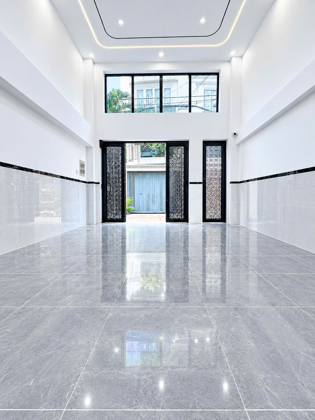 Tầng trệt lát đá của một tòa nhà cho thuê, cửa sắt hoa văn mở ra hẻm