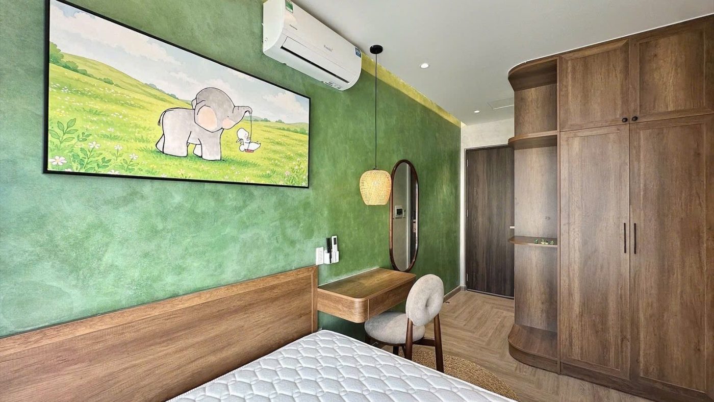 Phòng cho thuê có mảng tường xanh lá treo tranh chú voi, tủ gỗ, bàn trang điểm và giường, ảnh bìa bài viết về tiền gửi ngân hàng mất giá