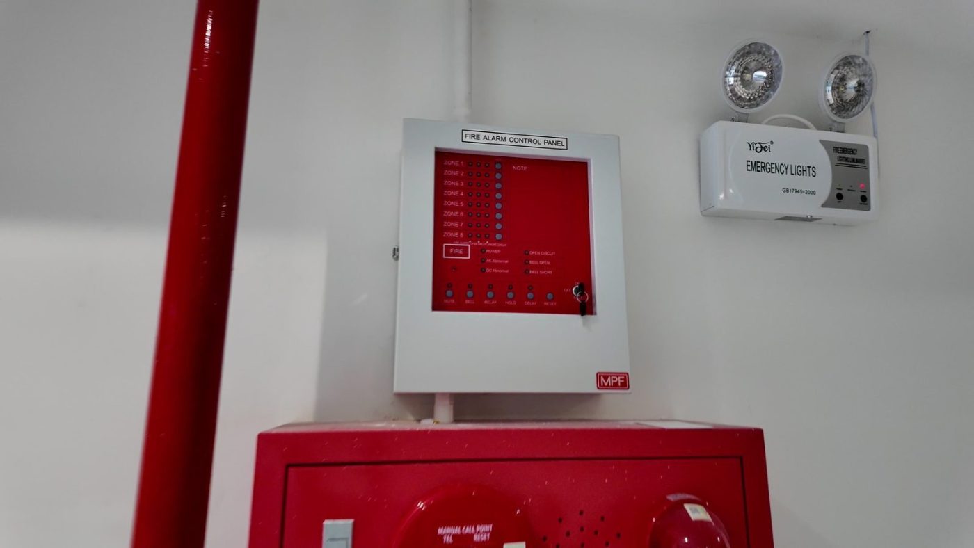 Tủ báo cháy trung tâm, đèn sự cố và hộp vòi chữa cháy màu đỏ ở tầng trệt một tòa nhà cho thuê