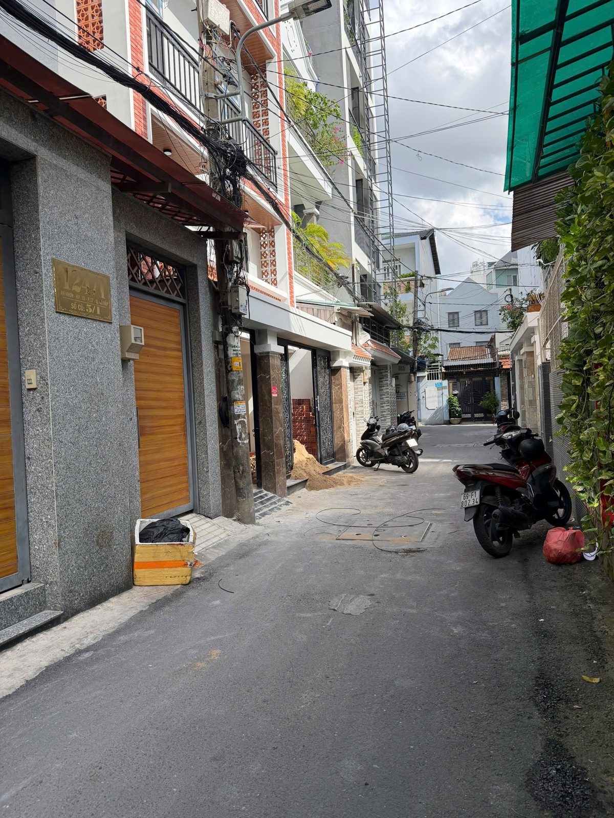 Con hẻm bê tông trước một tòa nhà cho thuê, hai bên là nhà phố