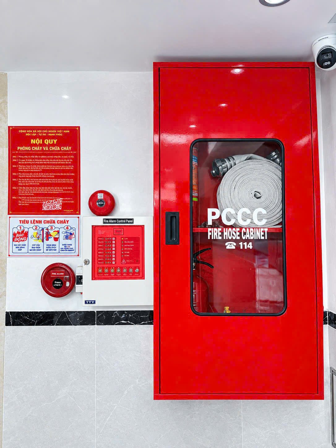 Tủ chữa cháy màu đỏ, chuông báo cháy và bảng nội quy trên tường tòa nhà cho thuê